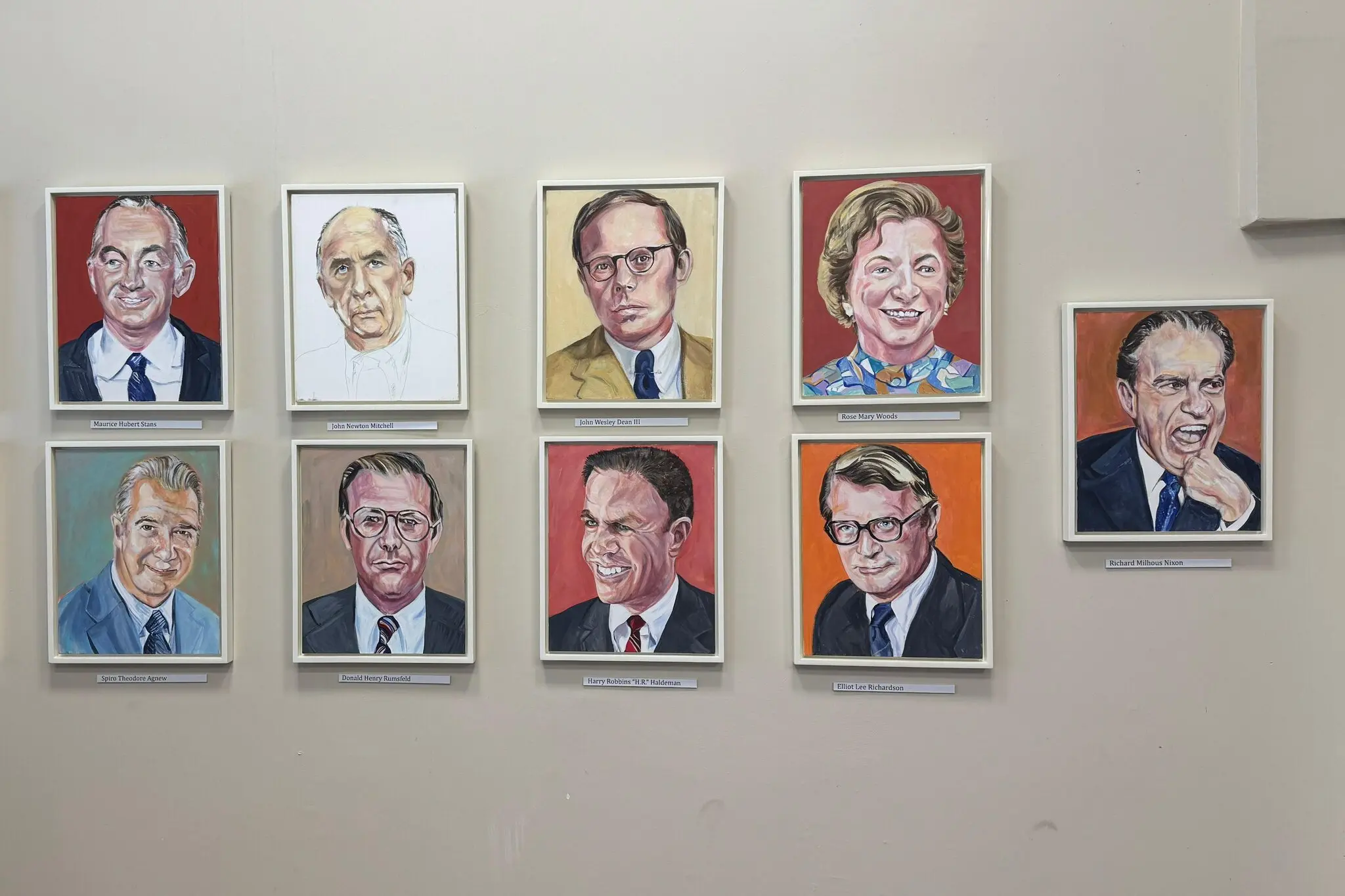Nine painted portraits of figures associated with Nixon, including Nixon himself, on a wall.